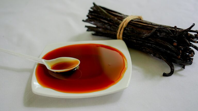 Best vanilla perfumes arranged on a warm wooden surface with vanilla bean pods