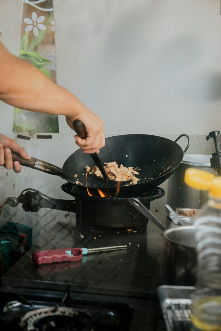 Carbon steel wok on gas burner showing seasoned patina, from the WanderSavvy how to buy and season a wok guide