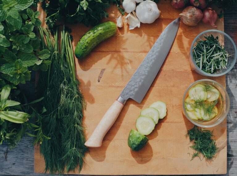 Best chef's knives under $100 laid out on a wooden cutting board in a home kitchen
